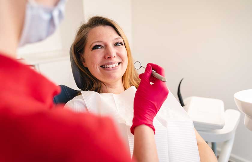 Untersuchung von Zähnen einer Patientin mit Dentalspiegel