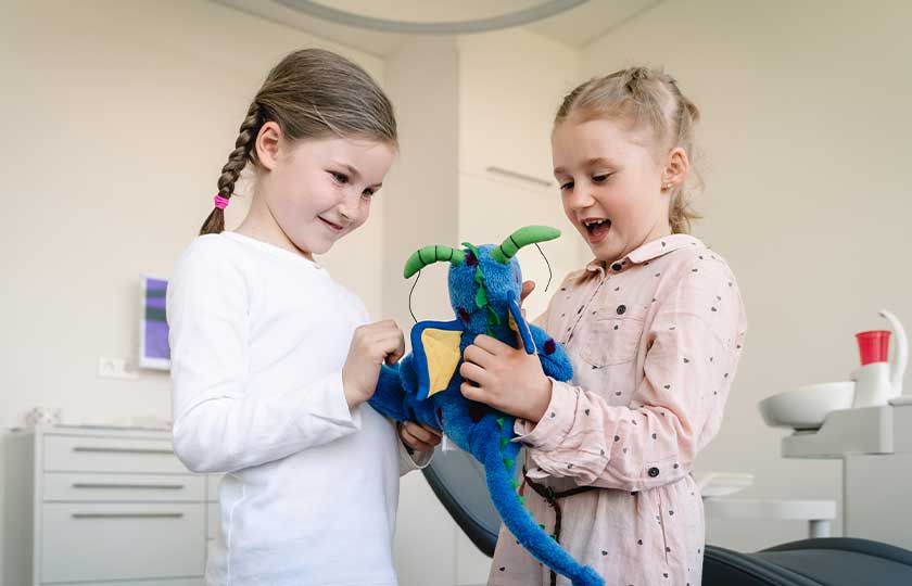 Zwei Mädchen spielen im MED:SMILE-Behandlungszimmer mit blauem Drachen.