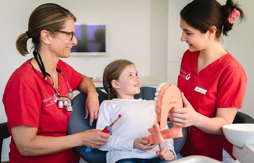 Dr. Wossidlo und MFA bei der Zahnputzschulung mit einer jungen Patientin