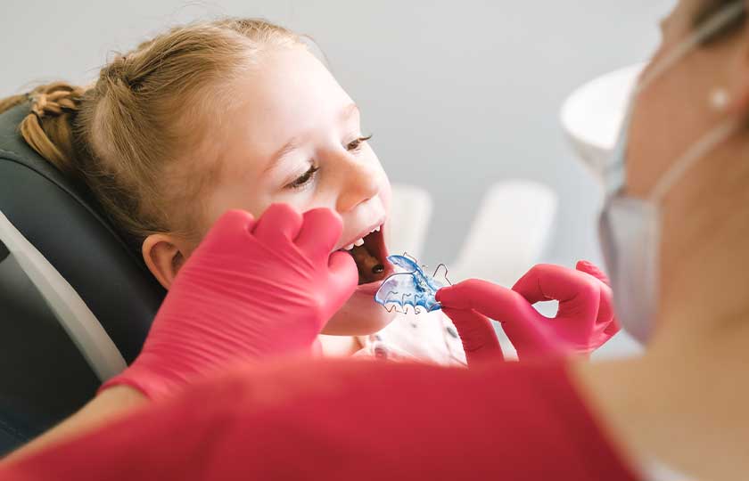 Behandlerin setzt junger Patientin eine herausnehmbare Zahnspange in den Oberkiefer ein