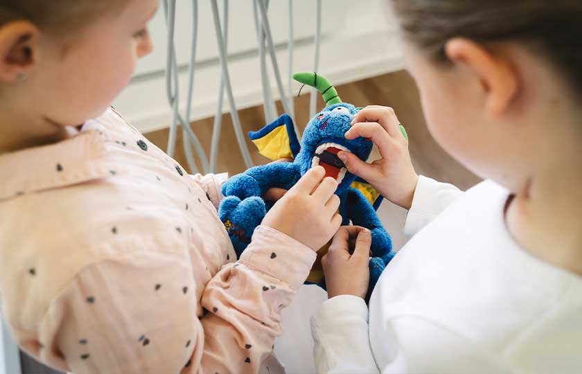 Zwei Kinder spielen im Wartebereich von MED:SMILE mit einem Plüschdrachen