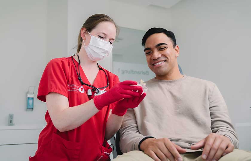 Dr. Romy Finsterer am Behandlungsstuhl im Gespräch mit Patienten.