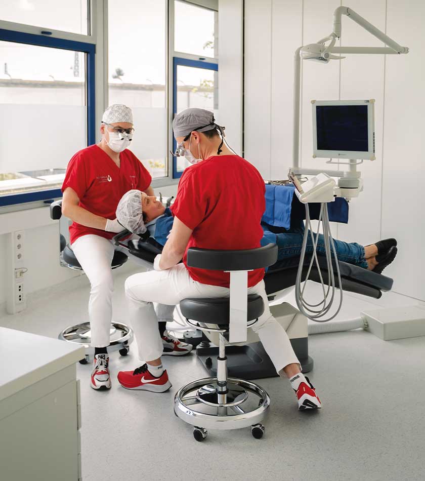 Dr. Jäger mit Mitarbeiterin am Behandlungsstuhl im Gespräch mit einer Patientin vor einer Implantation