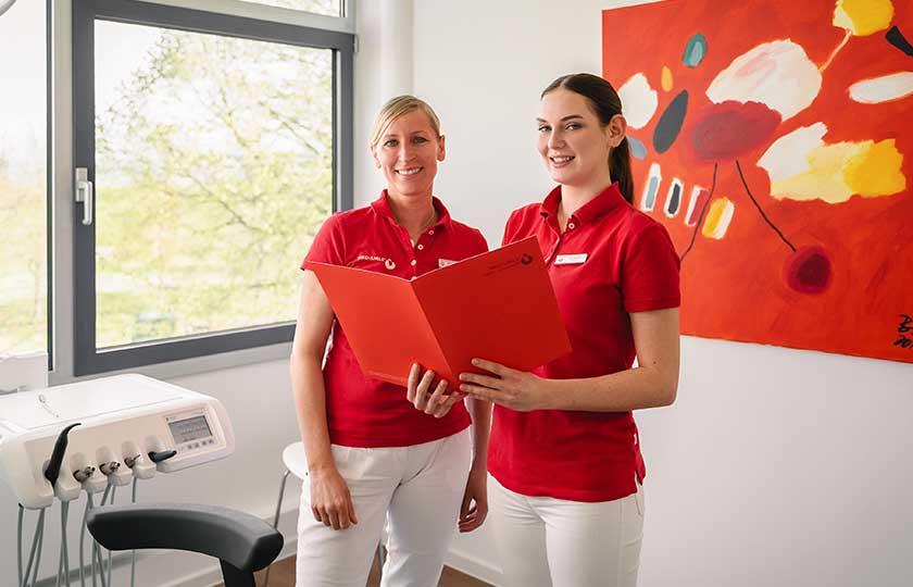 Zwei MED:SMILE-Mitarbeiterinnen schauen im Behandlungszimmer in eine Akte