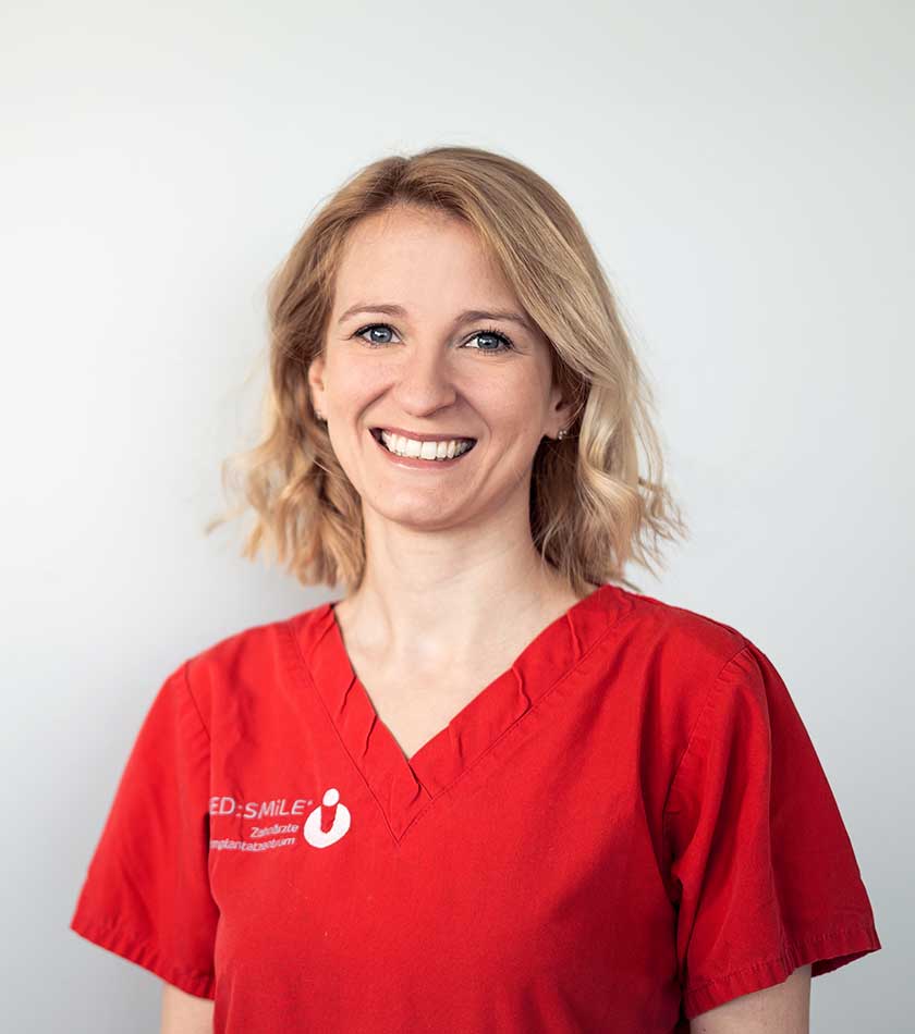 Zahnärztin Anne-Kathrin Hendler im rotem Schlupfkasack mit MED:SMILE-Logo.